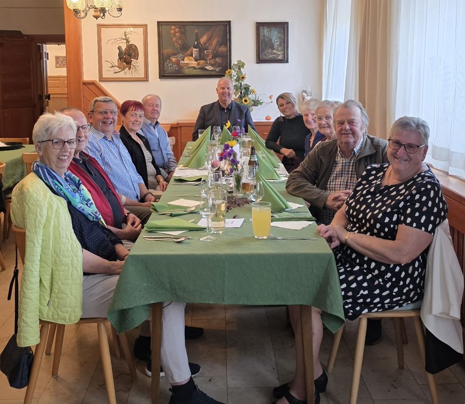 Gruppe von Menschen sitzt an einem Tisch mit grüner Tischdecke in einem Restaurant