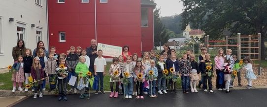 Schulkinder mit Sonnenblumen vor der Neuen Mittelschule in St. Martin im Innkreis